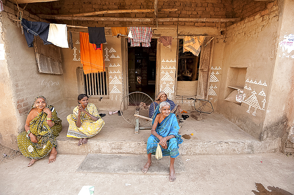 Women sitting chatting on verandah, painted with traditional Orissa patterns in rice flour, Naupatana weaving village, Orissa, India, Asia