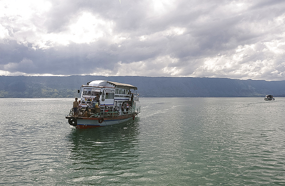 Ferry boat on Lake Toba arriving into Parapat beneath gathering monsoon clouds, Sumatra, Indonesia, Southeast Asia, Asia