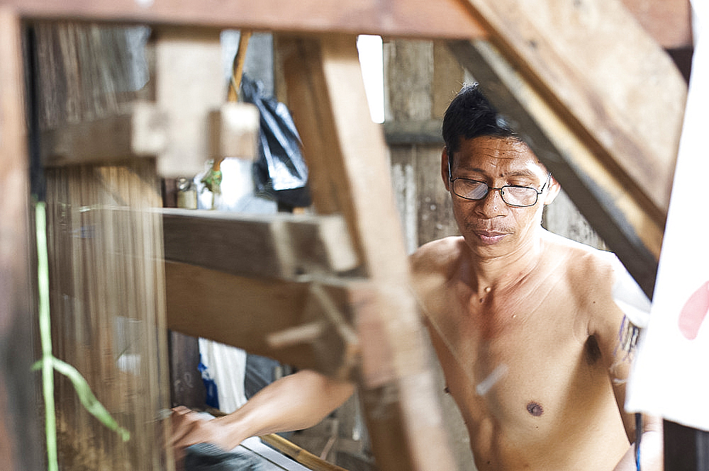 Silk weaver working on a traditional wooden loom in a factory in Pekalongan, Java, Indonesia, Southeast Asia, Asia