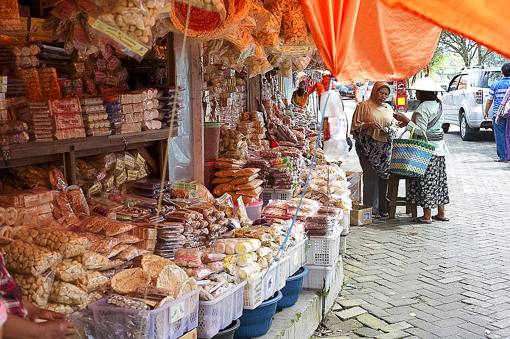 Local women chatting by a rural market stall selling rice based snacks, biscuits and cakes, Solo river valley, Java, Indonesia, Southeast Asia, Asia