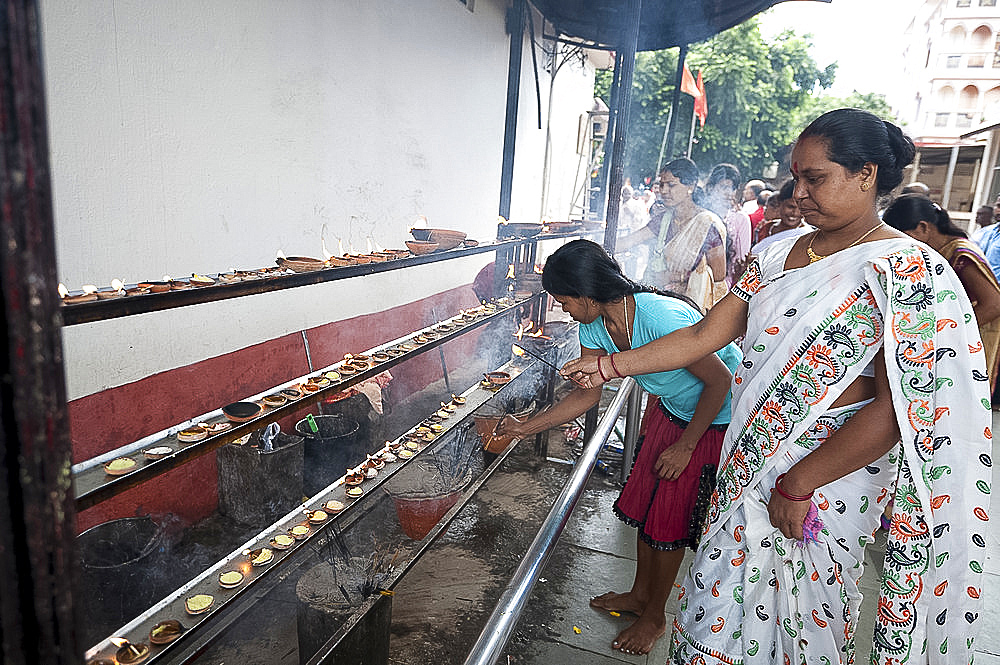 Hindu woman in white sari performing puja by lighting diya (candle) in Kamakhya temple, Guwahati, Assam, India, Asia