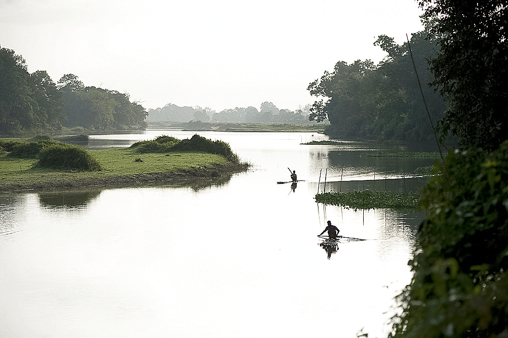 Early morning local village fishermen paddling flat, homemade bamboo rafts along the Diphlu River, Jorhat district, Assam, India, Asia