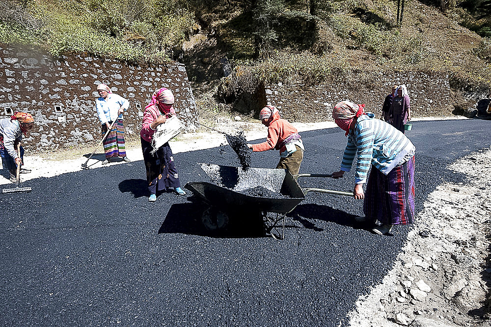 Female roads workers spreading hot tar to resurface roads after monsoon damage high in the hills of Arunachal Pradesh, India, Asia