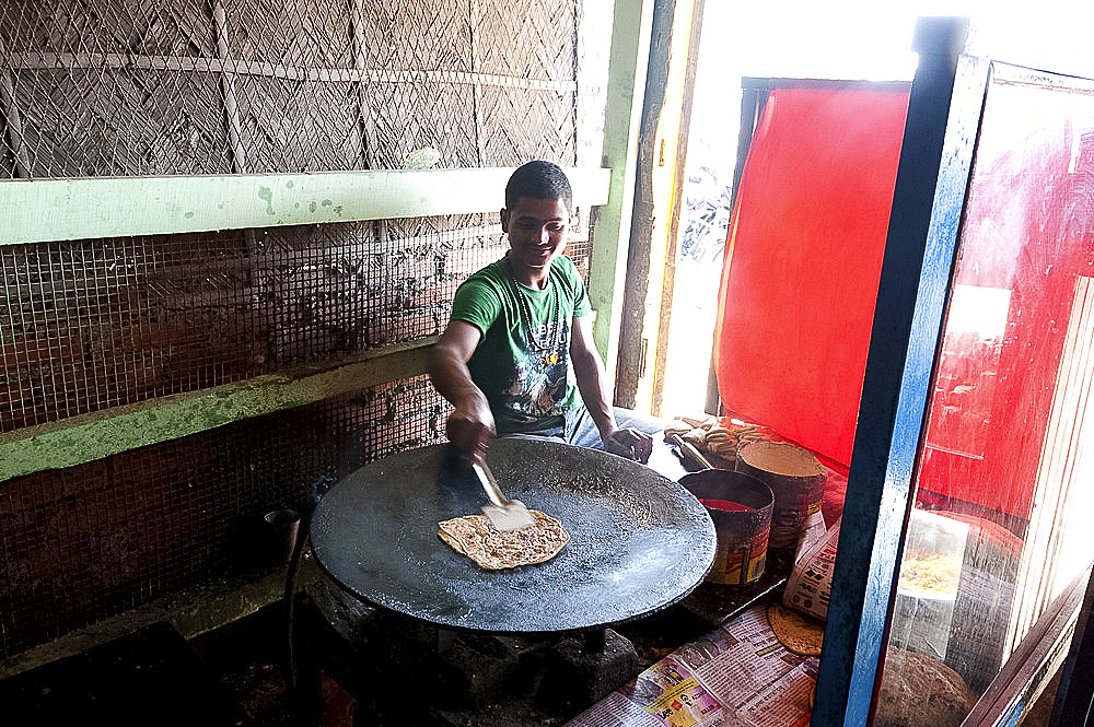 Young man cooking chapati in roadside dhaba, Balipara, Assam, India, Asia