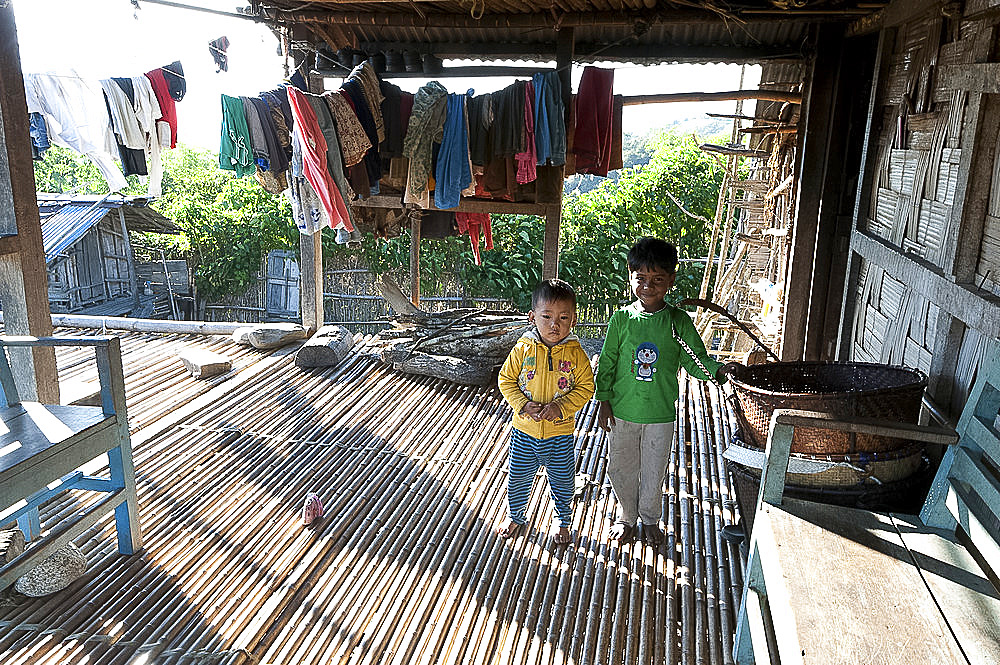 Two young Apatani tribal brothers on the bamboo verandah of their traditional house in late afternoon, Ziro, Arunachal Pradesh, India, Asia