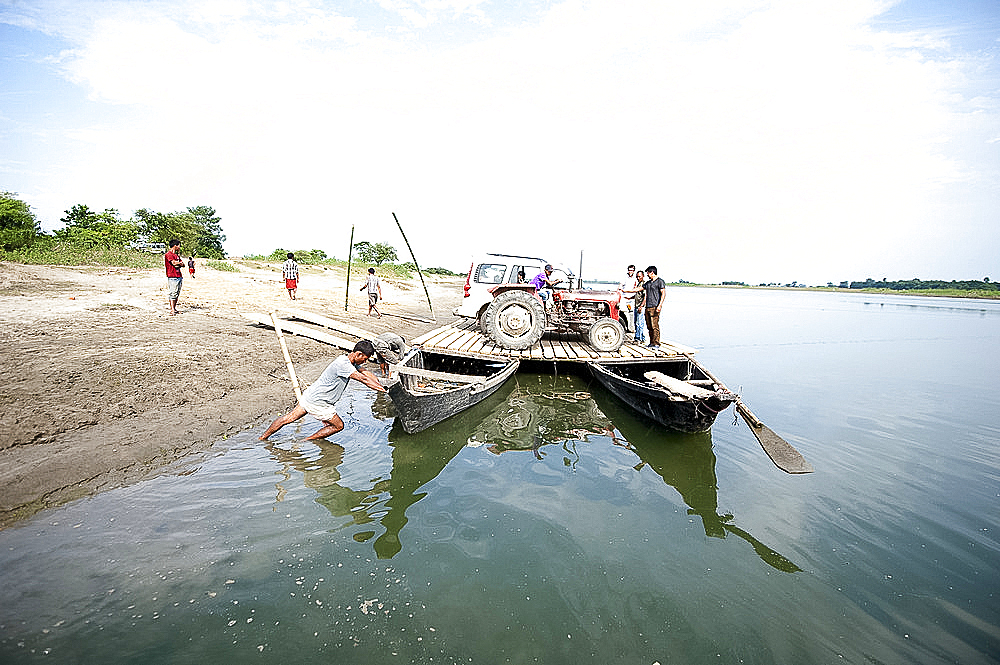 Car and tractor on a simple village ferry made from two wooden boats and wooden platform, Brahmaputra river, Majuli, Assam, India, Asia