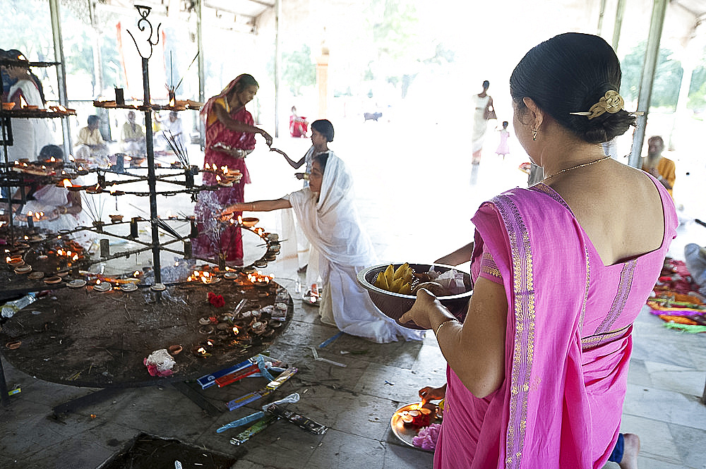 Hindu woman carrying puja offerings to Lord Siva, and others lighting candles in Sivadol Mandir, Sivasagar, Assam, India, Asia