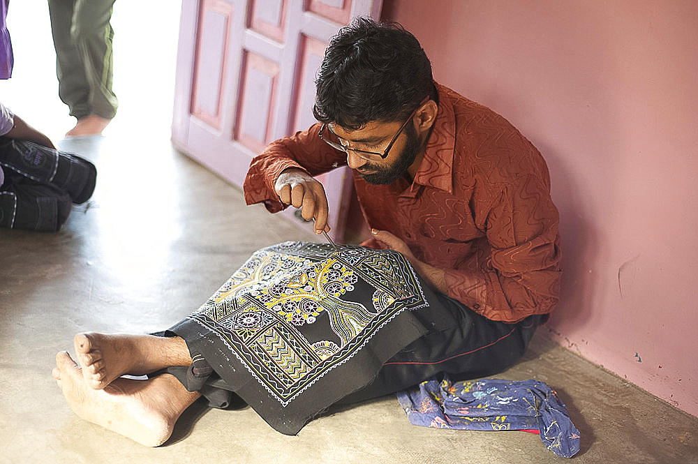 Muslim man making detailed Rogan art design on cotton fabric using boiled castor oil and pigment, Nirona, Kachchh, Gujarat, India, Asia