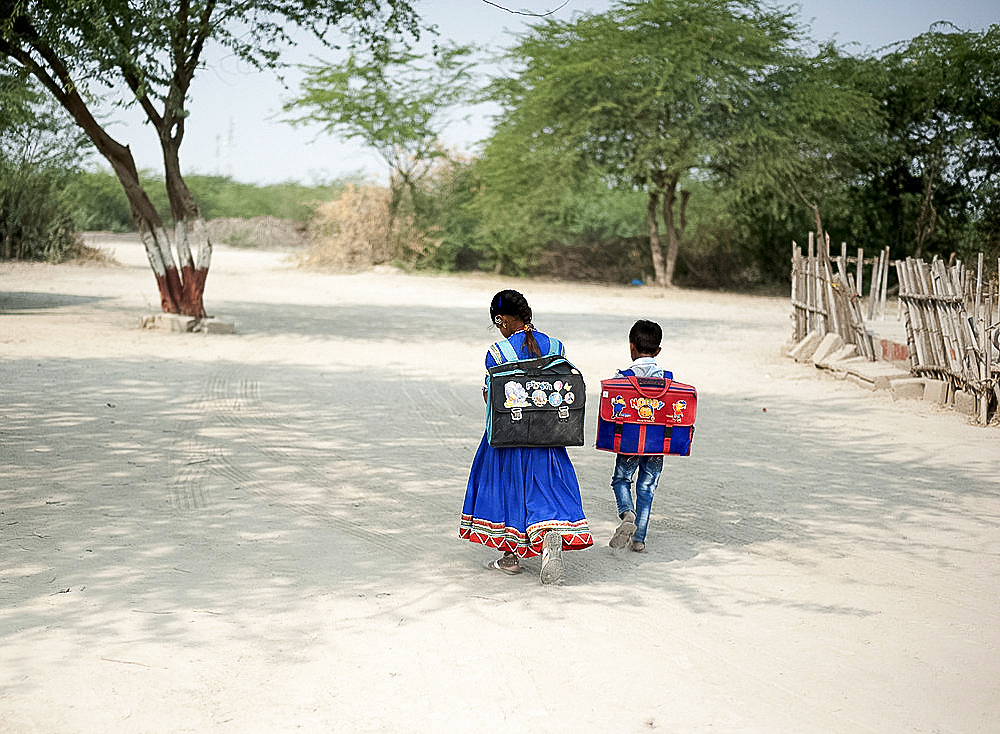 Young boy, and girl in Gujarati skirt, with satchels, walking to school, Bhirindiara, Kachchh (Kutch), Gujarat, India, Asia