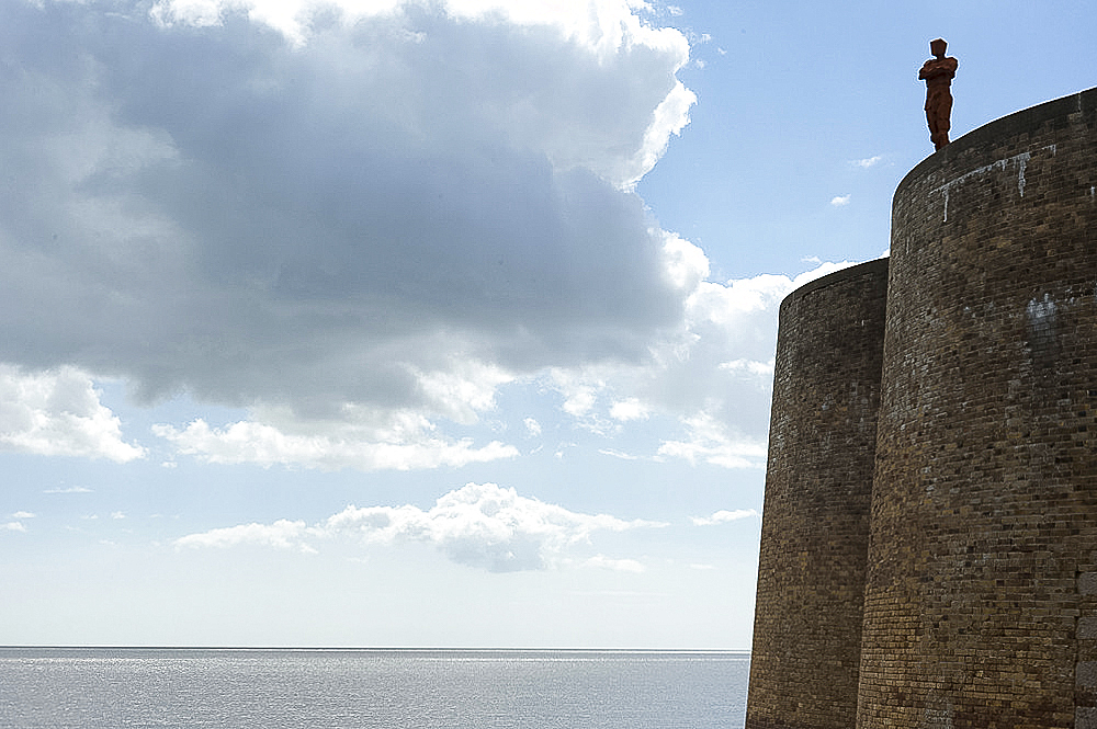 Antony Gormley's sculpture of a man looking out to sea, standing on the Napoleonic Martello tower in Aldeburgh, Suffolk, England, United Kingdom, Europe