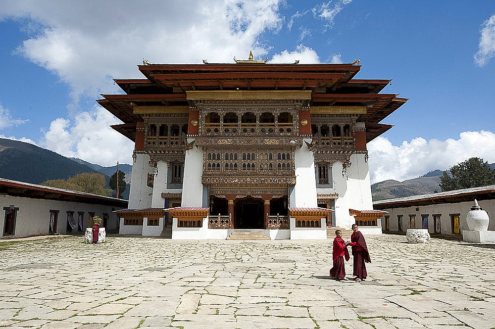 Buddhist monks in stone courtyard of Gangtey dzong (monastery), the largest Nyingmapa monastery in Bhutan, Asia