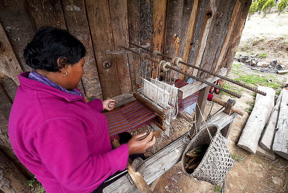 Woman weaving a length of Kira fabric on her domestic hand made wooden loom, from hand spun and dyed wool, Ura, Eastern Bhutan, Asia