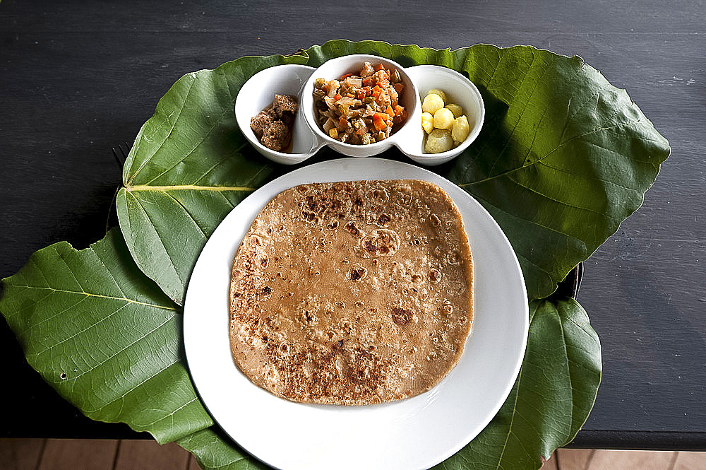 Burmese lunch of chapati with beef curry, vegetables and potatoes, served on teak leaf mat, Kalaw, southern Shan state, Myanmar (Burma), Asia