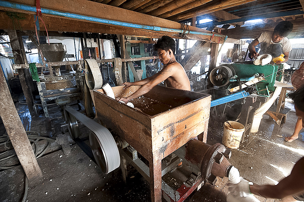 Men squeezing cooked rice through a machine before pressing into flat sheets to make fresh rice noodles, Hsipaw, Shan state, Myanmar (Burma), Asia