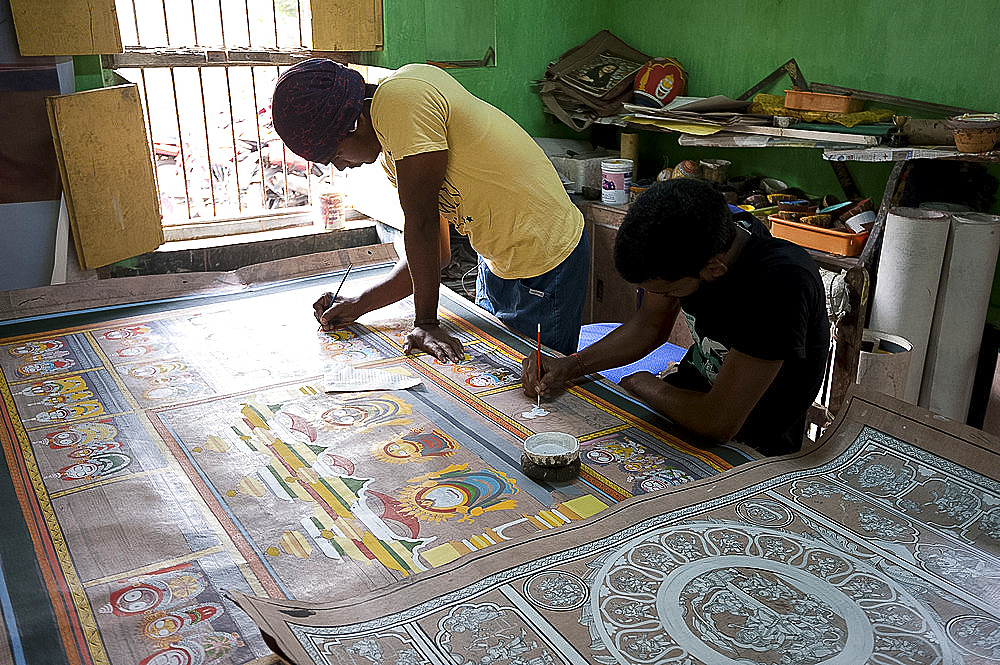 Pattachitra artists painting large traditional Odishan scroll Thia Badhia painting on cloth of the temple of Hindu god Jagannath, Odisha, India, Asia