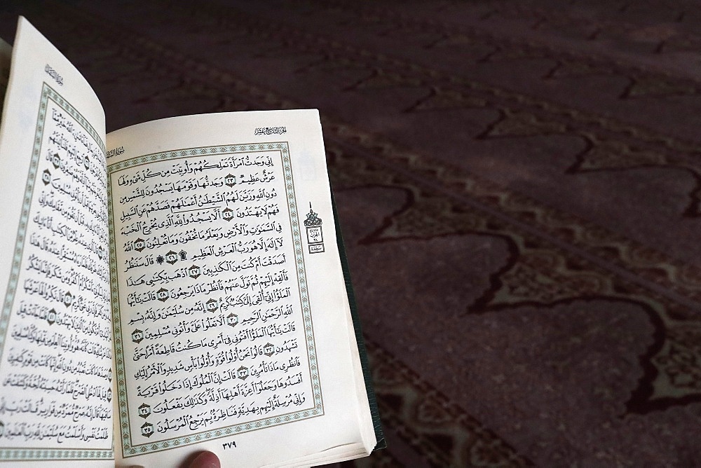 Close up on hand with open Quran, Putra Mosque (Masjid Putra), Putrajaya, Malaysia, Southeast Asia, Asia