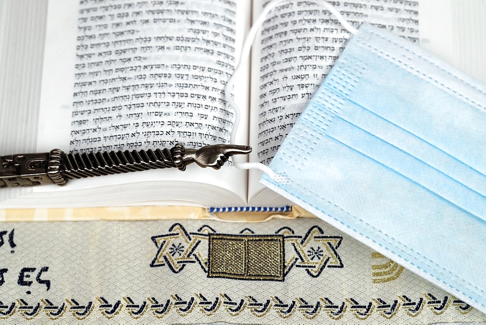 A silver Yad Jewish ritual pointer on a Torah and surgical mask, France, Europe