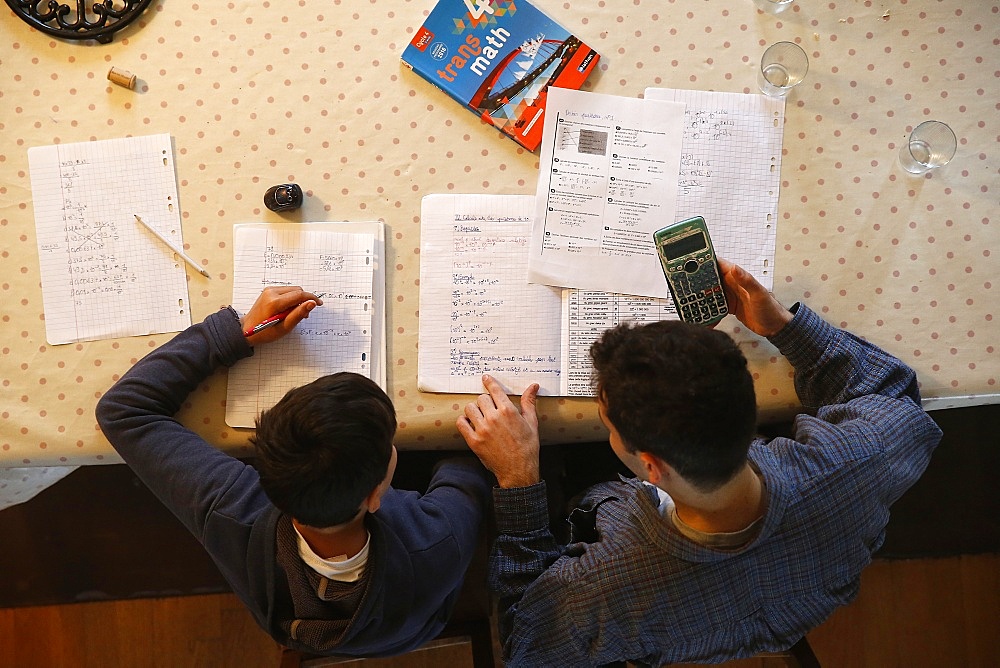 Young man helping a boy with his homework in Montrouge, France, Europe