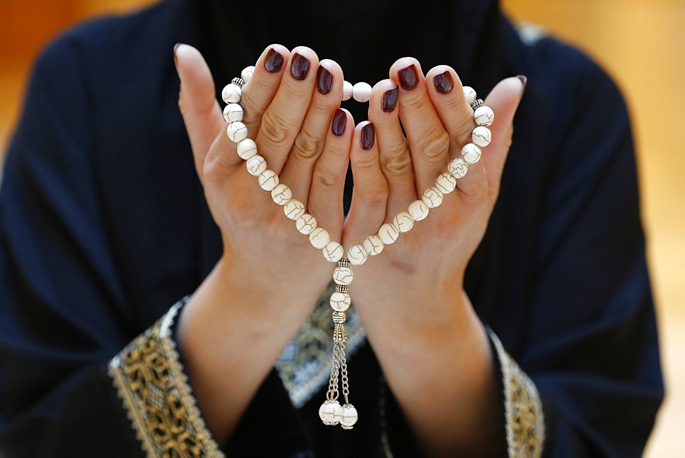 Close up of a Muslim woman's hands in abaya while holding rosary and praying, United Arab Emirates, Middle East