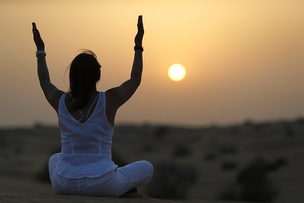 Sunset meditation in the desert at sunset, as concept for religion, faith, prayer and spirituality, Dubai, United Arab Emirates, Middle East