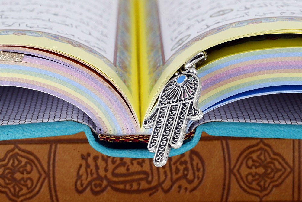 Open Holy Quran with Hamsa (Hand of Fatima) symbols of Muslim faith and religion, France, Europe