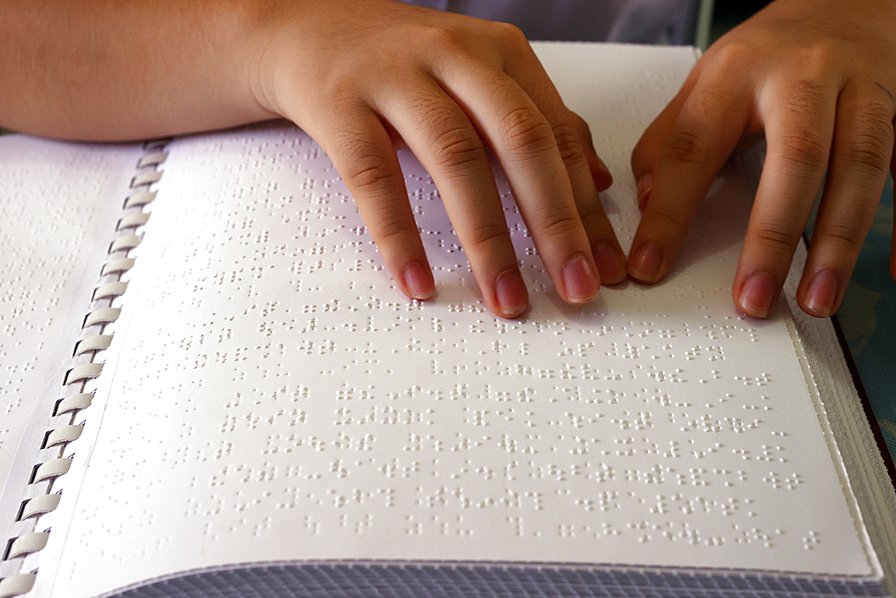 Close up on hands of blind girl reading braille book, Center for Blind Children, Ho Chi Minh City, Vietnam, Indochina, Southeast Asia, Asia