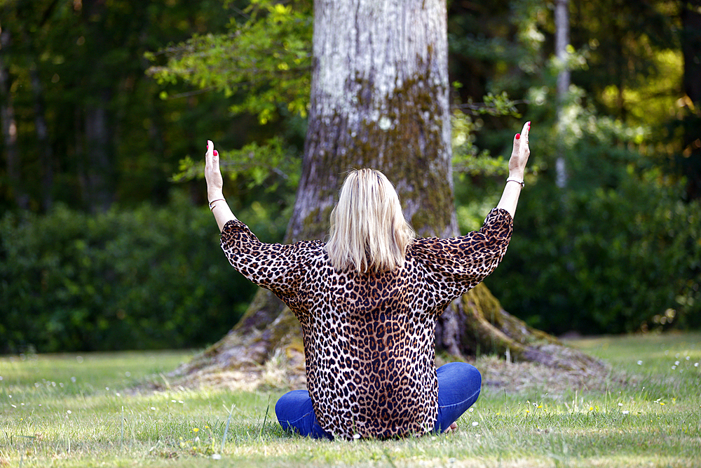 Christian woman spending personal time in and praying outdoors in a park, France, Europe