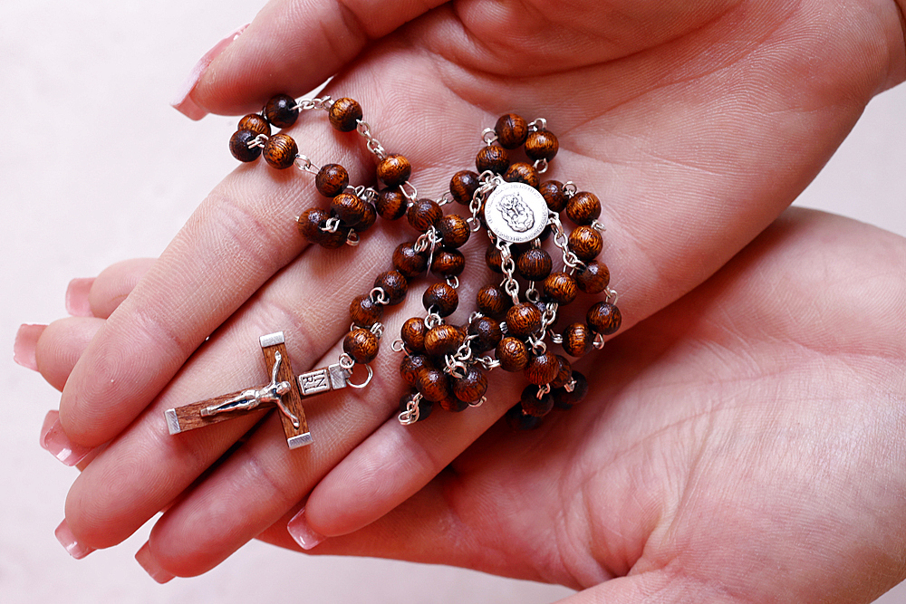 Woman's hands holding wood Catholic rosary in prayer, Vietnam, Indochina, Southeast Asia, Asia