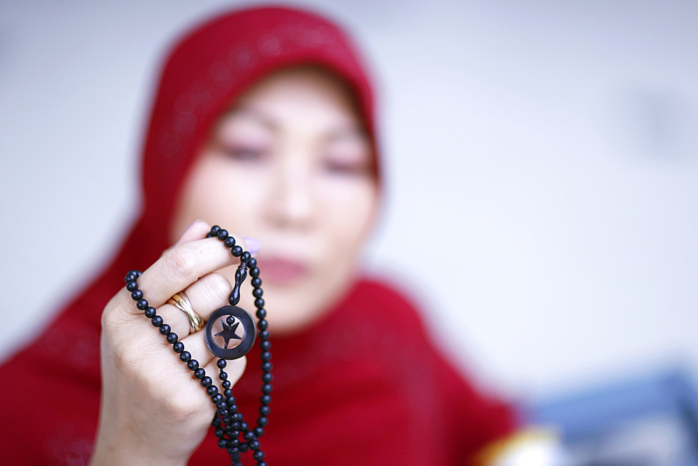 Muslim woman praying with islamic beads in hand, religious meditation, worship, Ramadan concept, Surabaya, Indonesia