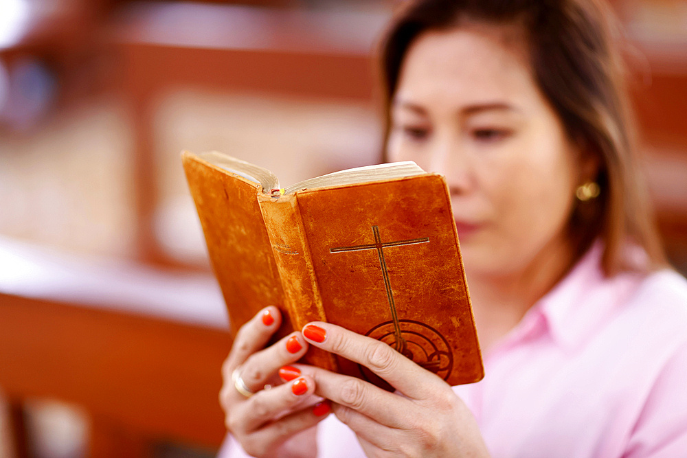 Woman reading an old Bible in a church, Tan Chau, Vietnam