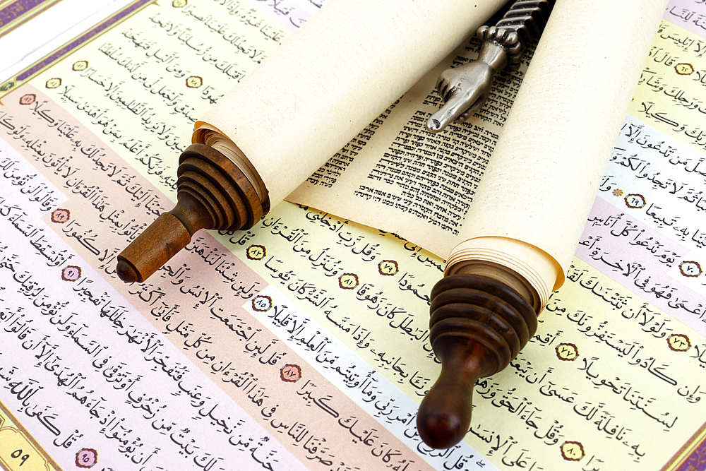 Torah scrolls in Hebrew, yad and quran in Arabic. Relationship between Muslims and Jews. Interfaith and peace concept.