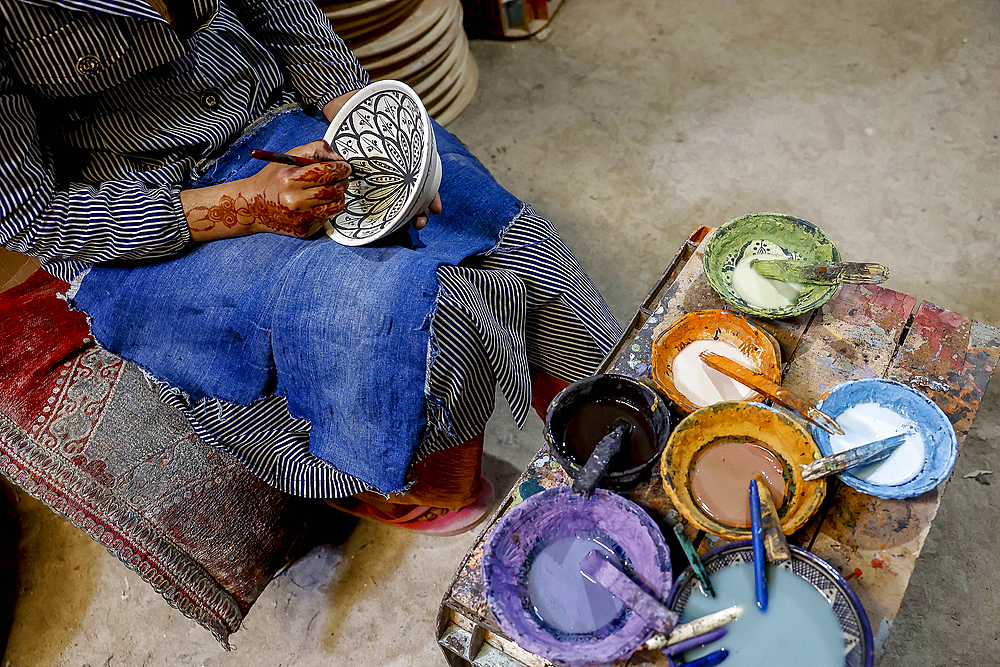 Worker painting bowls in a pottery workshop, Safi, Morocco