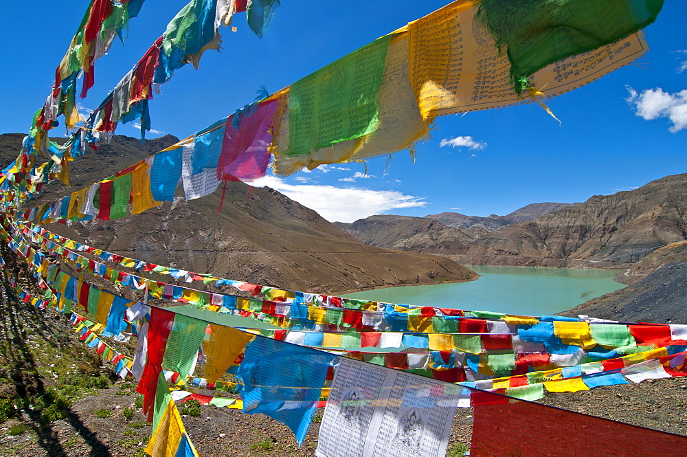 Prayer flags above an artifical lake near the Karo-La Pass, Tibet, China, Asia