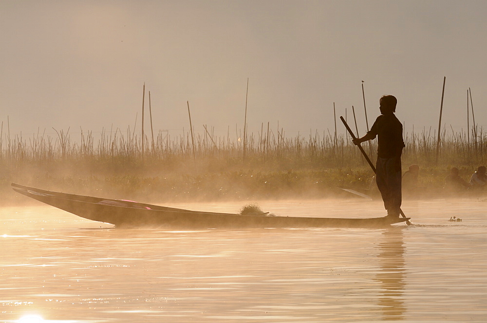 Man rowing his little rowing boat at sunrise on Inle Lake, Shan States, Myanmar, Asia