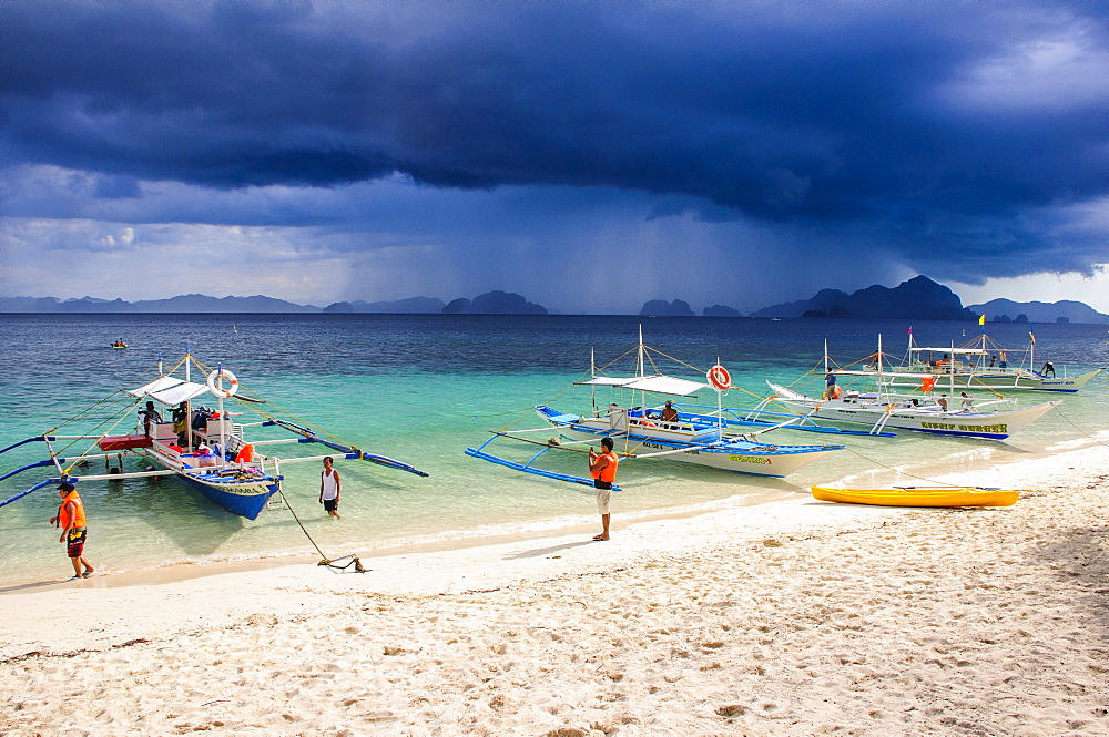 Outrigger boats before a strom anchoring on a sandy beach  in  the Bacuit archipelago, Palawan, Philippines, Southeast Asia, Asia