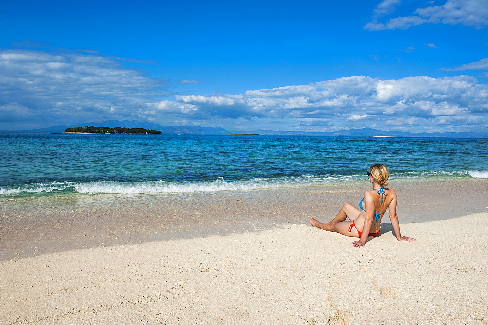 Woman sitting on a the white sand beach of Beachcomber Island, Mamanucas Islands, Fiji, South Pacific, Pacific