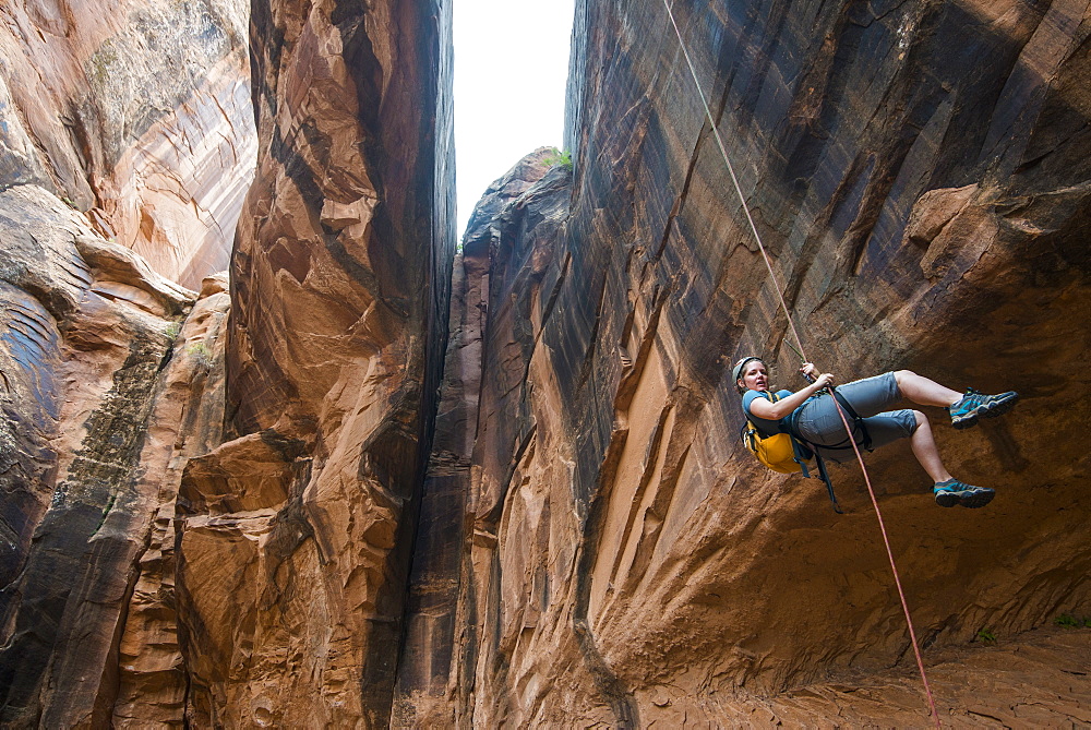 Woman rapelling down a giant arch, canyoneering, Moab, Utah, United States of America, North America