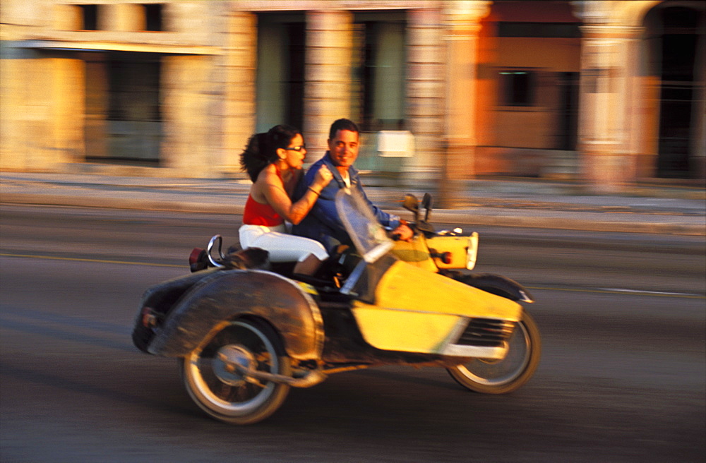 Cuba, Havana, Young couple on a motorcycle motoring along the Malecon, Havana, Cuba, West Indies, Central America