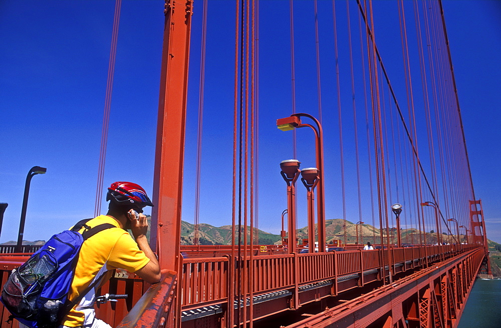 Cyclist using cell phone on the Golden Gate Bridge, San Francisco, California, United States of America, North America