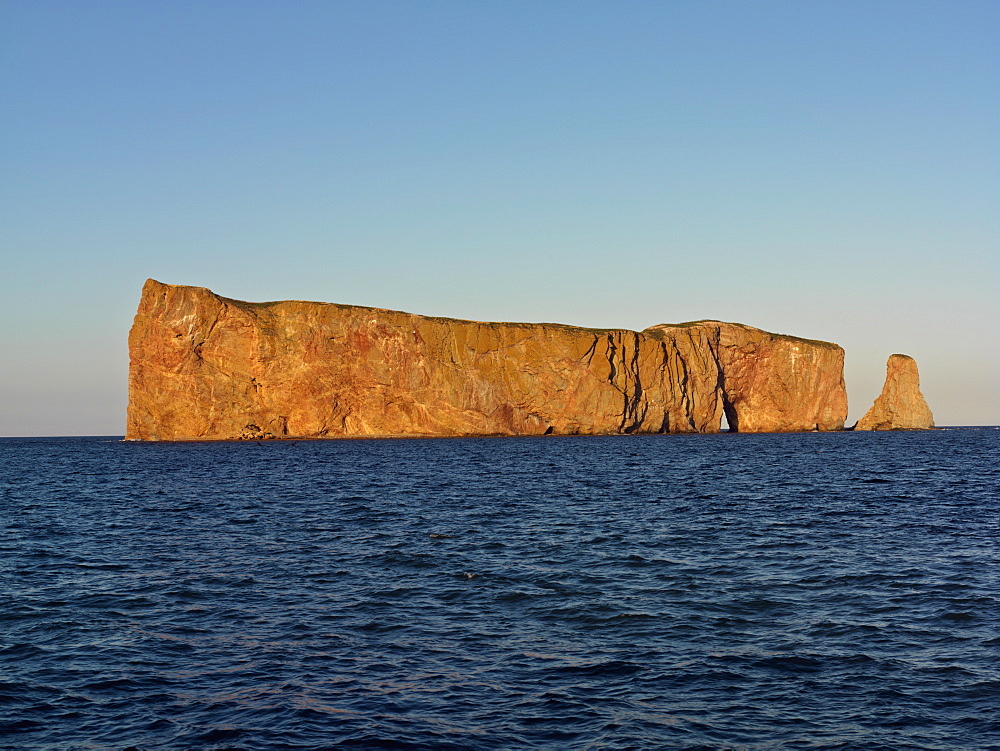 Perce Rock illuminated at sunset at high tide and the Gulf of St. Lawrence, Perce, Gaspesie, Quebec, Canada, North America