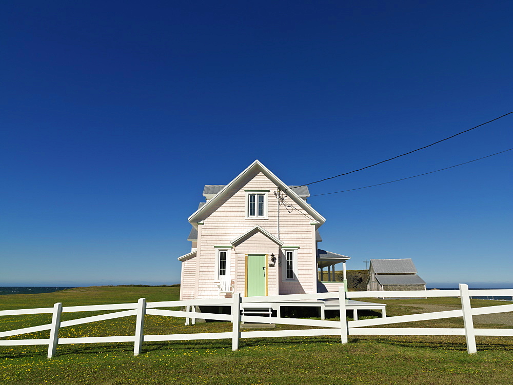 Pink house and with white fence against a blue sky, Riviere-la-Madeleine, Gaspesie, Quebec, Canada, North America