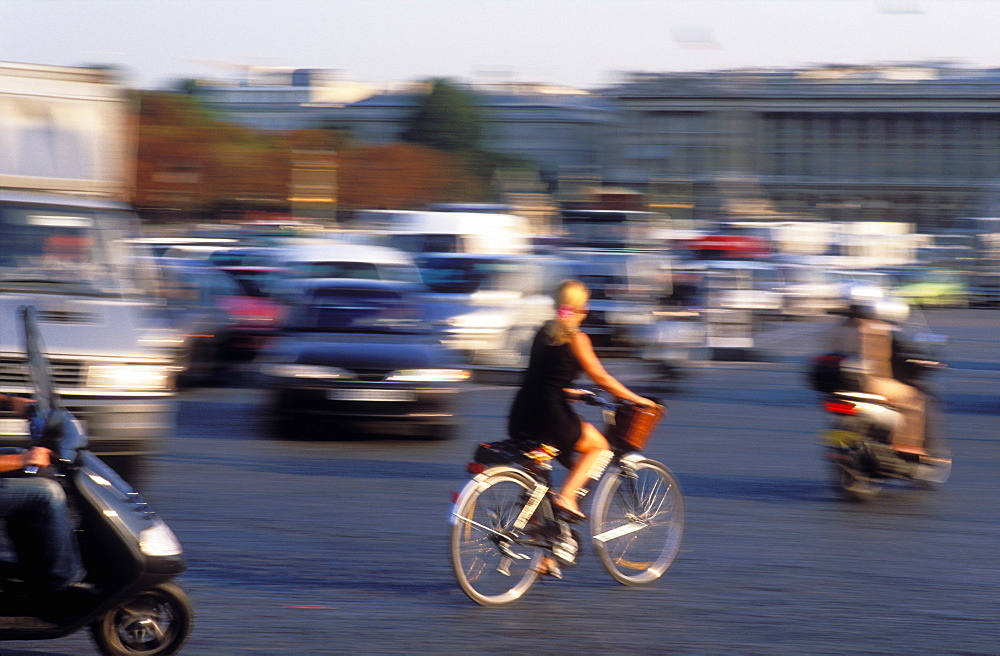 Cyclist in traffic in the Place de la Concorde, and Eiffel Tower behind, Paris, France, Europe