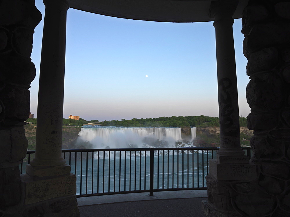 View of American Falls at dusk with moonrise through pillars of a pavilion on the Canadian side, Niagara Falls, Ontario, Canada, North America