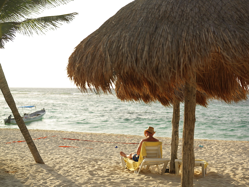 Man relaxing under palapa on beach, Mayan Riviera, Akumal, Yucatan, Quintana Roo, Mexico, North America