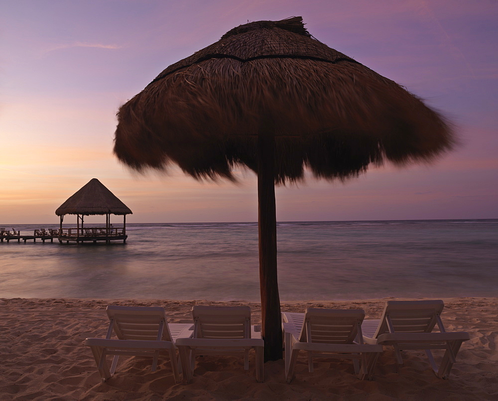 Chairs under a palapa, with pier beyond at sunrise, Mayan Riviera, Akumal, Yucatan, Quintana Roo, Mexico, North America