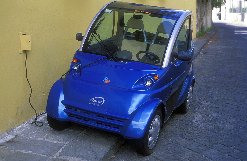 Electric car being charged at wall outlet, Florence, Tuscany, Italy, Europe