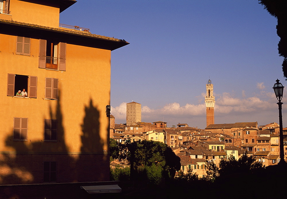 Elderly couple at window with view of Siena skyline, Siena, Tuscany, Italy, Europe