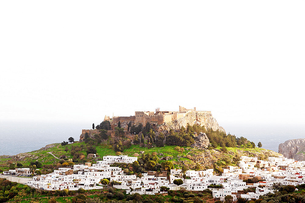 White houses below the fortified citadel of the acropolis at Lindos on Rhodes, Dodecanese, Greek Islands, Greece, Europe