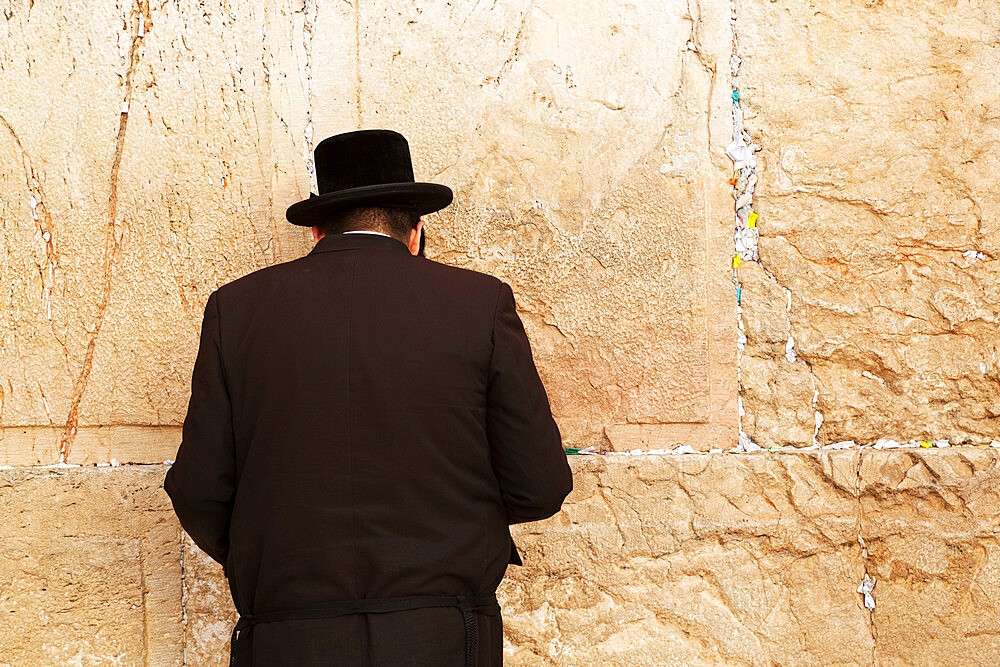 A Jewish man wearing Orthodox clothing prays by the Western Wall (Wailing Wall), Jerusalem, Israel, Middle East