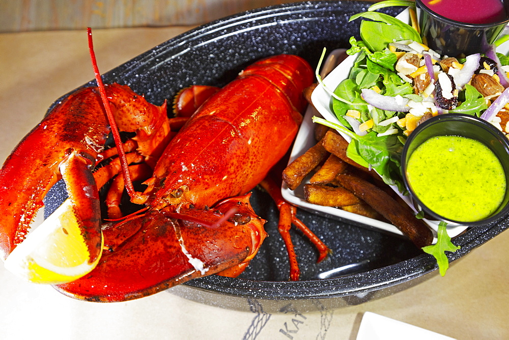 A lobster dinner served with salad, sauces and French fries in Barrington, Nova Scotia, Canada, North America